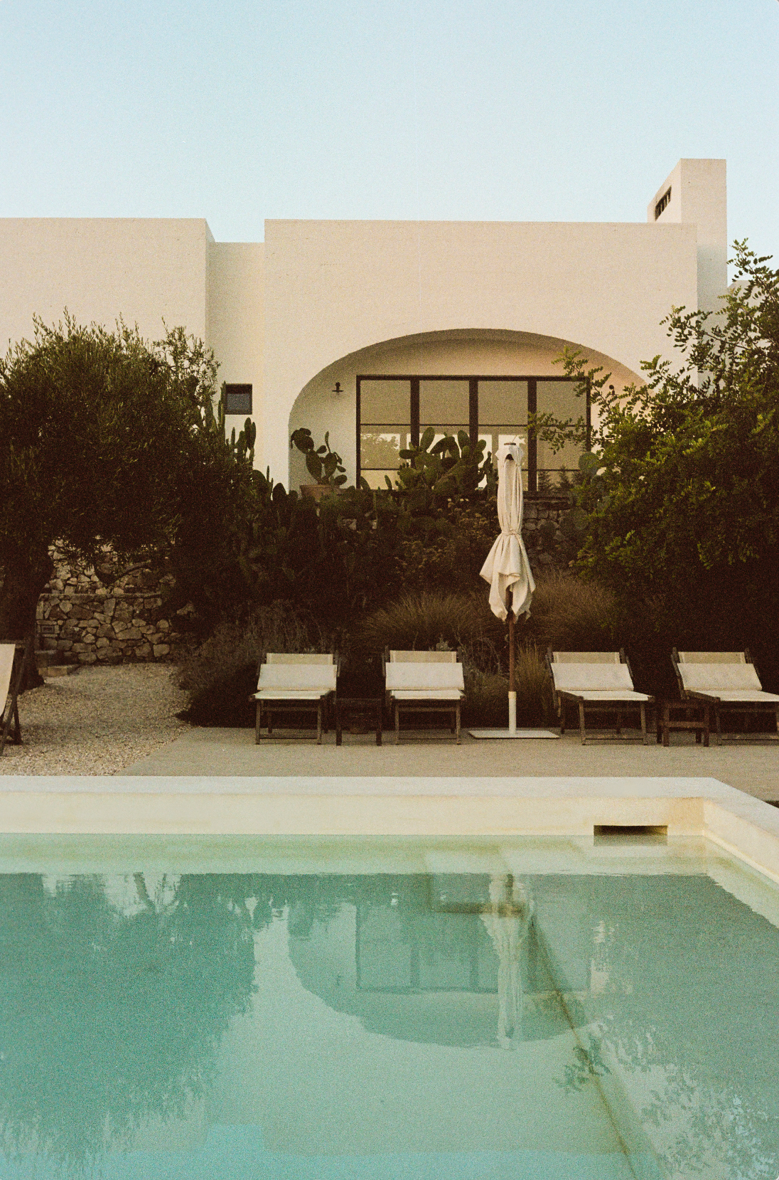 Photograph of a farm house and sun louges by the pool in Puglia, Italy.