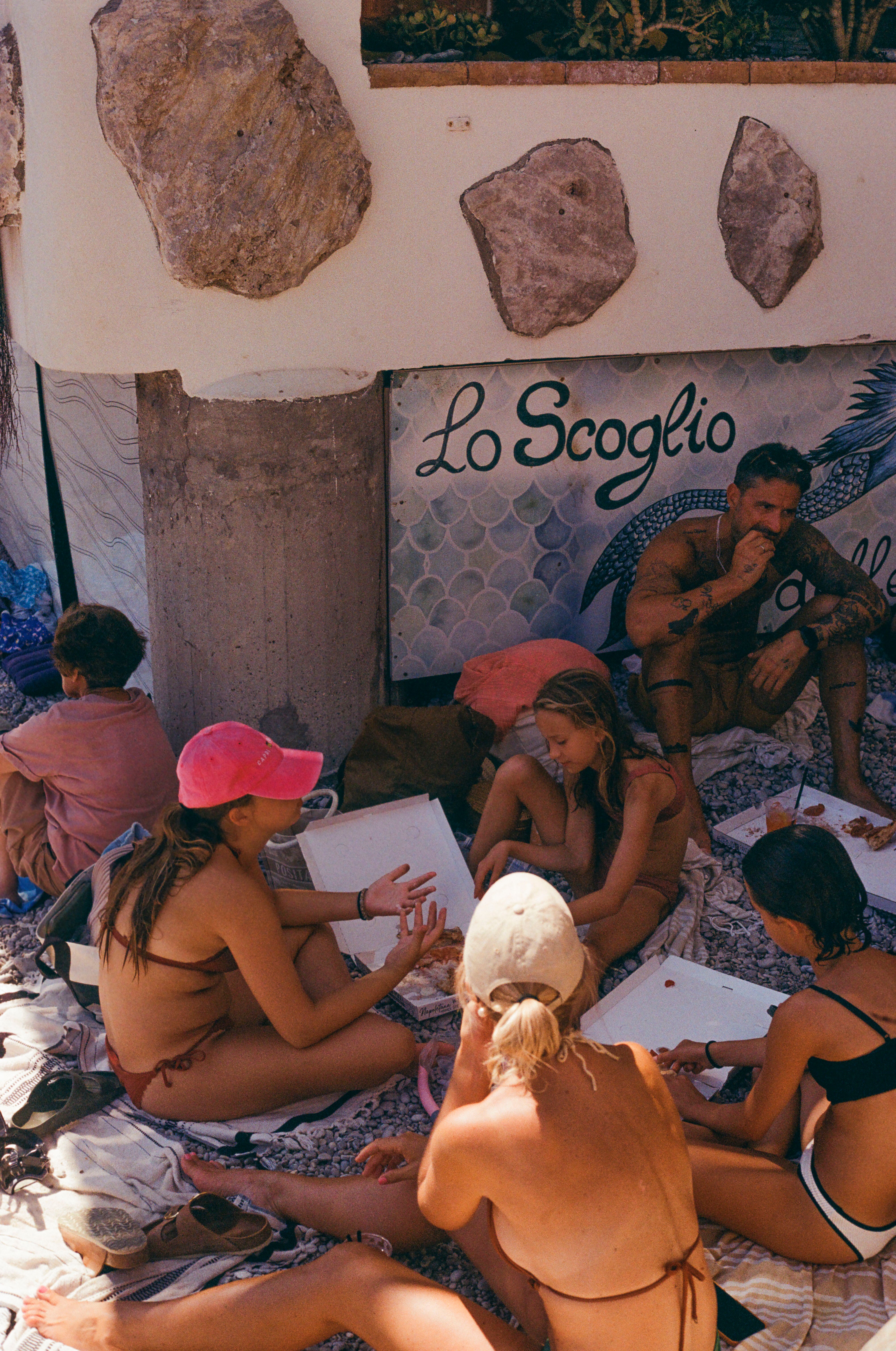 Photograph of a young Italian family eating pizza on the beach at Marina Picola beach in Capri, Italy.