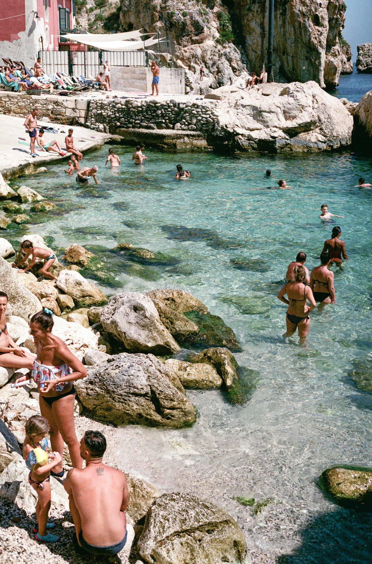Photograph of swimmers in the sea along the Scopello shoreline in Sicily, Italy.